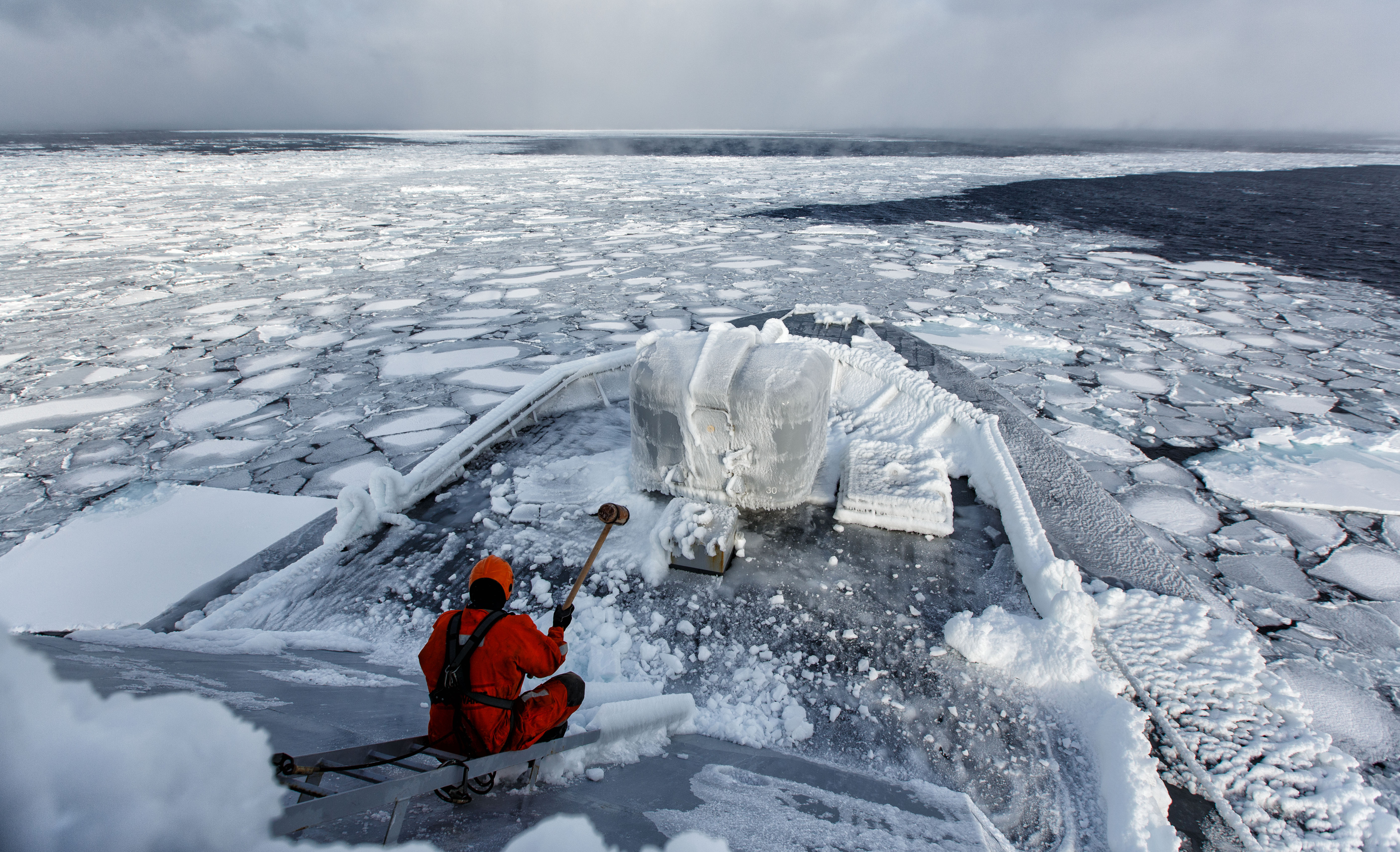 Fartøy som seiler i et isete og snøbelagt vinterlandskap.
